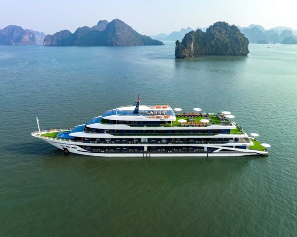 Aerial view of a luxurious cruise ship sailing through Halong Bay's emerald waters with towering lim.