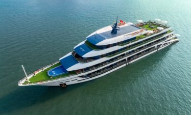 Aerial view of a luxurious Halong Bay cruise ship sailing through emerald waters, showcasing eleganc.