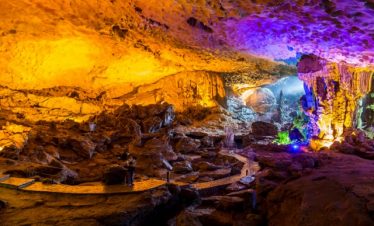 Vivid cave interior illuminated with colorful lights, showcasing an adventurous underground experien.