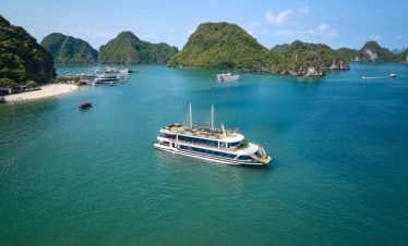 Stunning view of a luxury cruise sailing through emerald waters surrounded by limestone karsts in Ha.