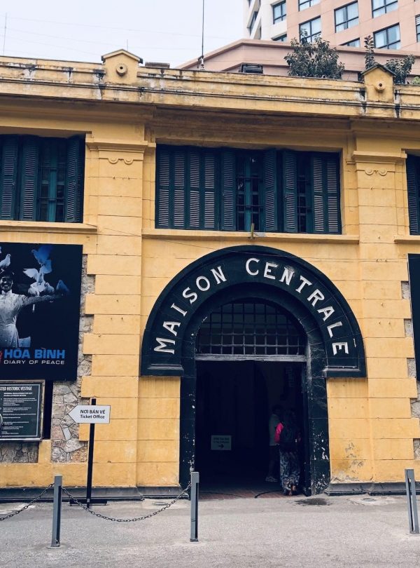 Vibrant scene outside Maison Centrale with travelers exploring historic architecture in Hanoi.