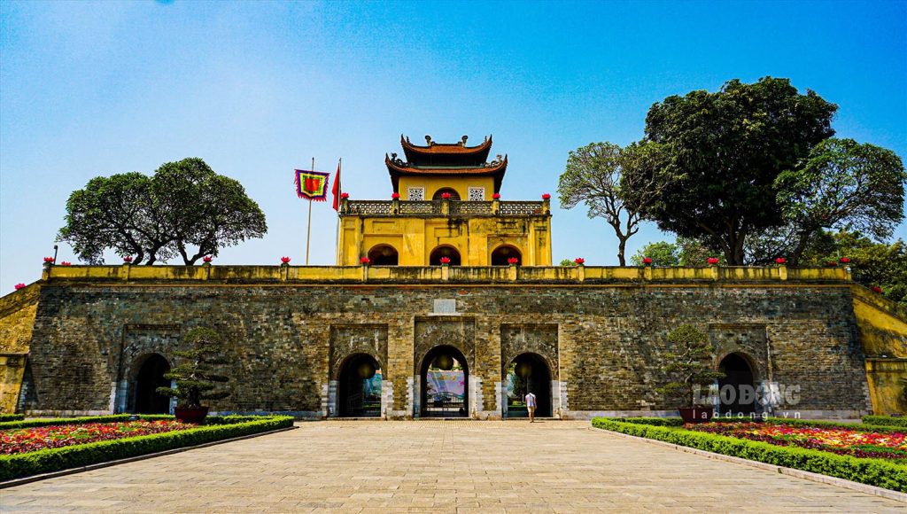 Ancient Vietnamese temple with traditional architecture, surrounded by lush trees and vibrant garden.