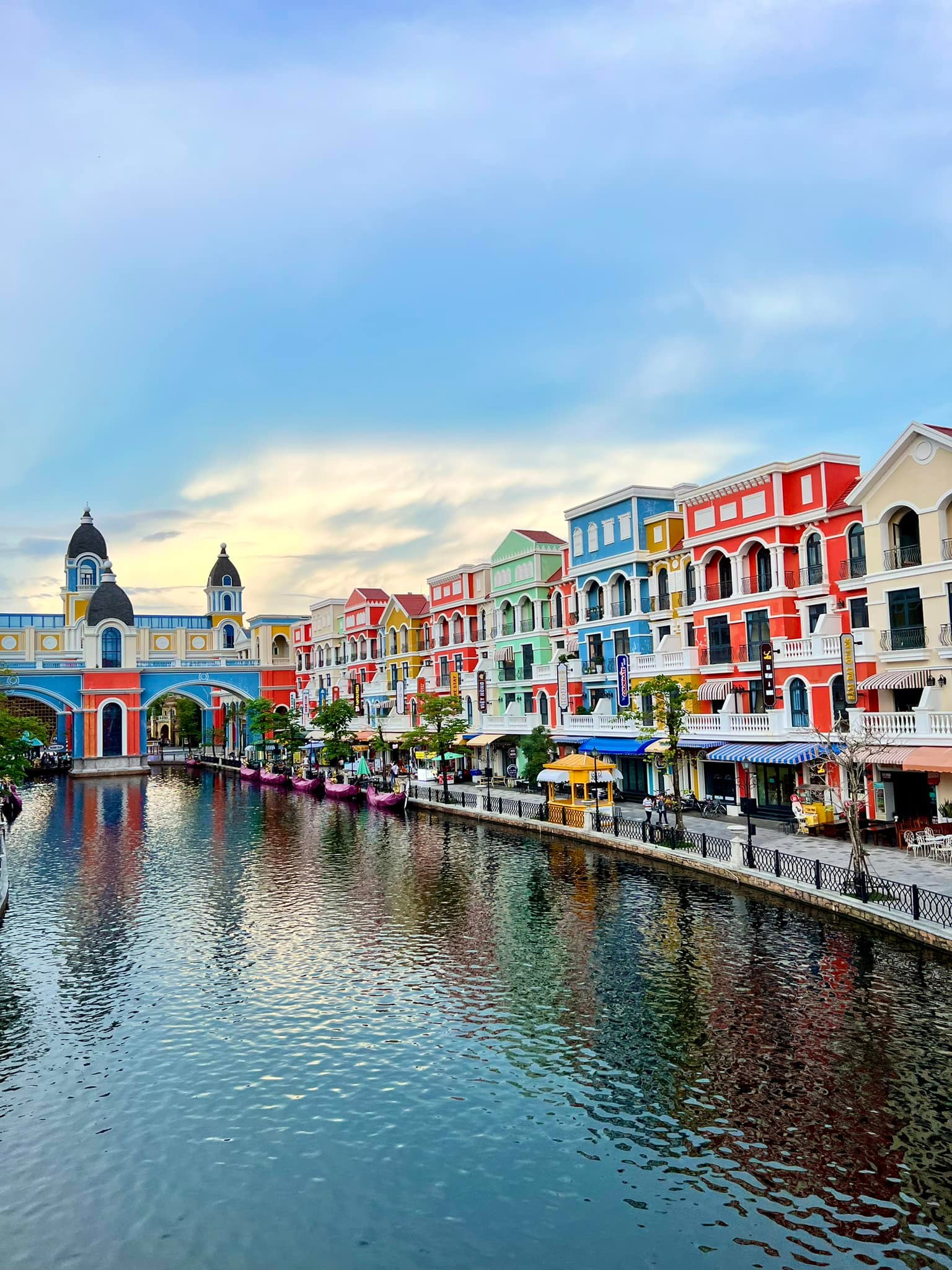Colorful European-style buildings along a canal in a vibrant Vietnamese town, showcasing charming architecture and lively atmosphere.