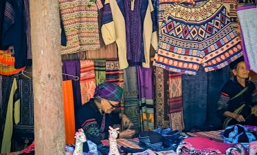 Colorful textile market scene in Sapa showcasing traditional Hmong clothing and handcrafted fabrics.
