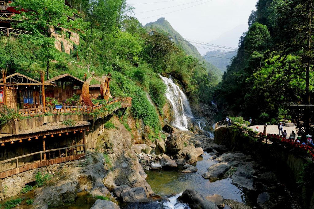 Scenic view of Sapa waterfall with vibrant greenery and mountain backdrop, perfect for trekking and.
