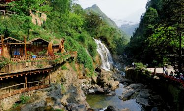Scenic view of Sapa waterfall with vibrant greenery and mountain backdrop, perfect for trekking and.