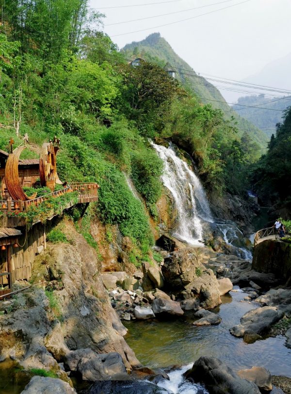 Scenic view of Sapa waterfall with vibrant greenery and mountain backdrop, perfect for trekking and.