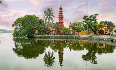 Scenic view of a traditional pagoda and lush greenery reflected in tranquil water at a historic site.