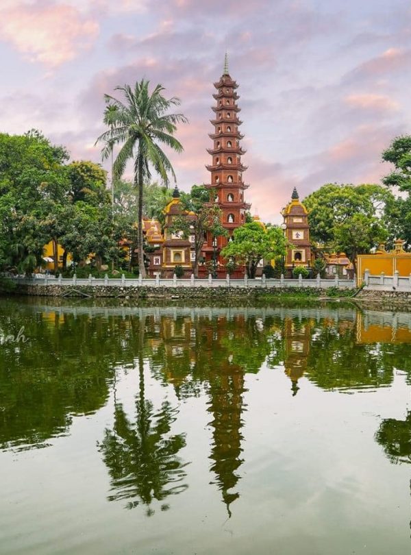 Scenic view of a traditional pagoda and lush greenery reflected in tranquil water at a historic site.