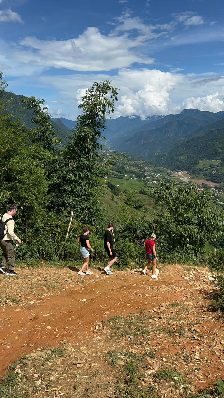 Hiking scene in Sapa with lush green mountains and trekkers enjoying the scenic trail.