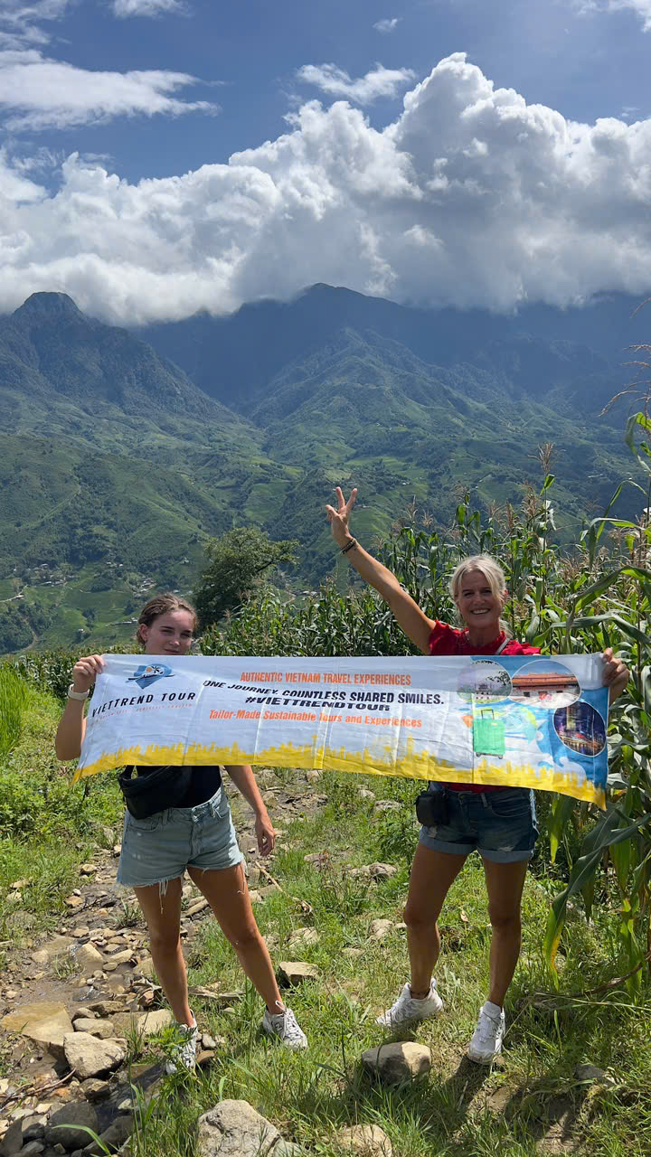 Beautiful mountain landscape in Sapa with travelers holding a ViettrendTour banner, enjoying outdoor.
