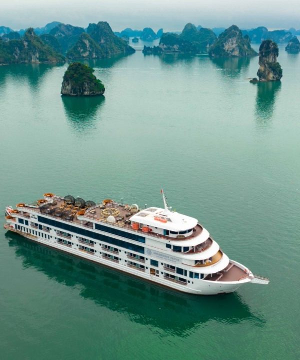 Halong Bay scenic view with cruise ship and limestone karsts, tranquil waters, and misty atmosphere.