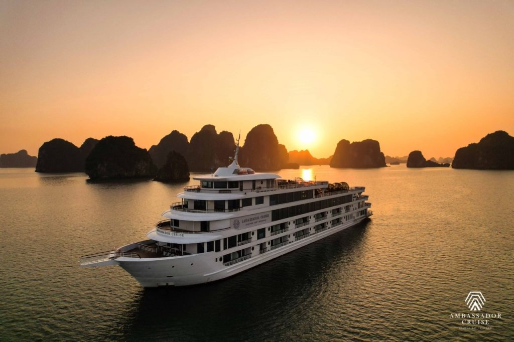 Luxurious cruise sailing through Halong Bay at sunset, showcasing stunning limestone karsts and tran.
