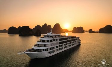 Luxurious cruise sailing through Halong Bay at sunset, showcasing stunning limestone karsts and tran.