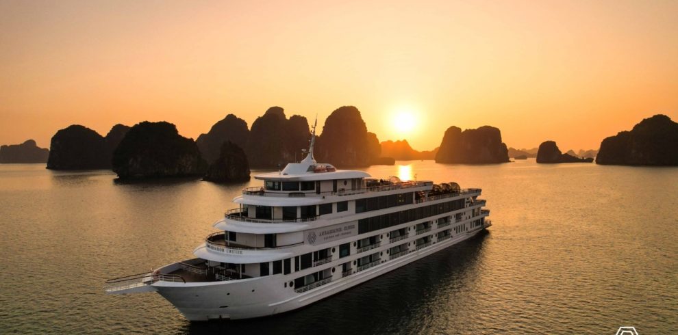 Luxurious cruise sailing through Halong Bay at sunset, showcasing stunning limestone karsts and tran.