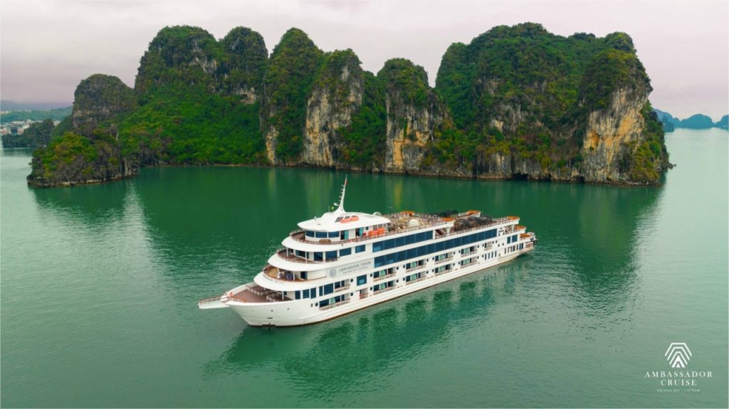 Luxurious cruise sailing past towering limestone karsts in Halong Bay, Vietnam, with calm emerald wa.