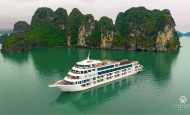 Luxurious cruise sailing past towering limestone karsts in Halong Bay, Vietnam, with calm emerald wa.