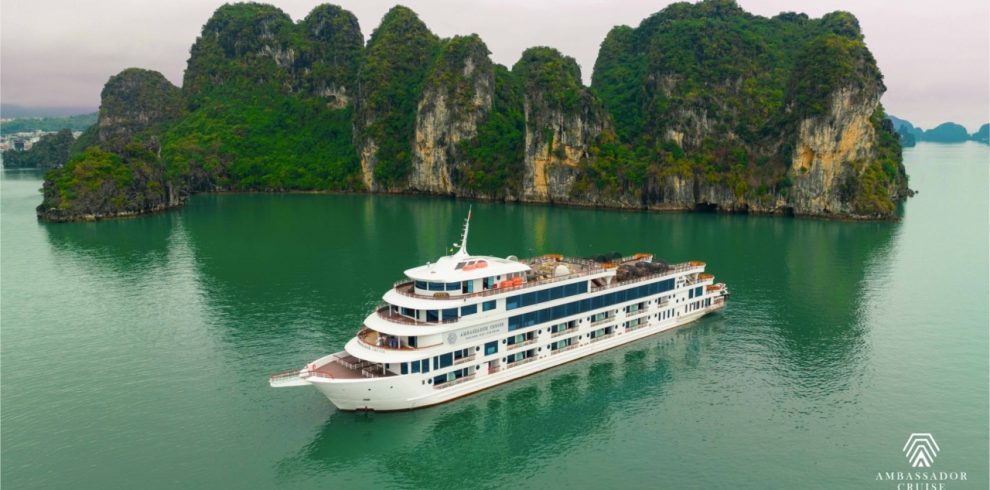 Luxurious cruise sailing past towering limestone karsts in Halong Bay, Vietnam, with calm emerald wa.