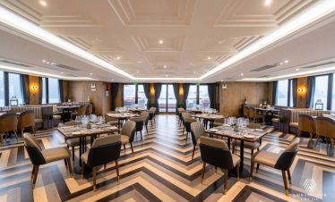 Luxurious cruise dining room with modern decor and panoramic bay views, perfect for a relaxing Halon.