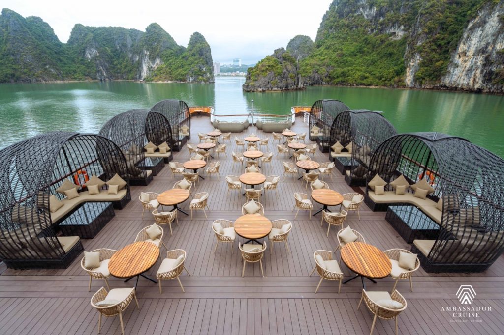 Stunning Halong Bay cruise balcony with modern seating and scenic limestone karsts in the background.