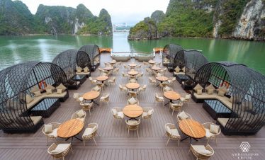 Stunning Halong Bay cruise balcony with modern seating and scenic limestone karsts in the background.