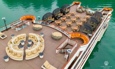 Stunning view of Halong Bay from cruise balcony with relaxing seating area and turquoise waters.