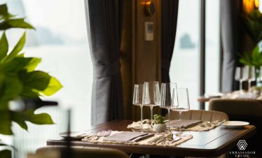 Stunning view from a cruise balcony in Halong Bay with elegant table setting and serene waters.