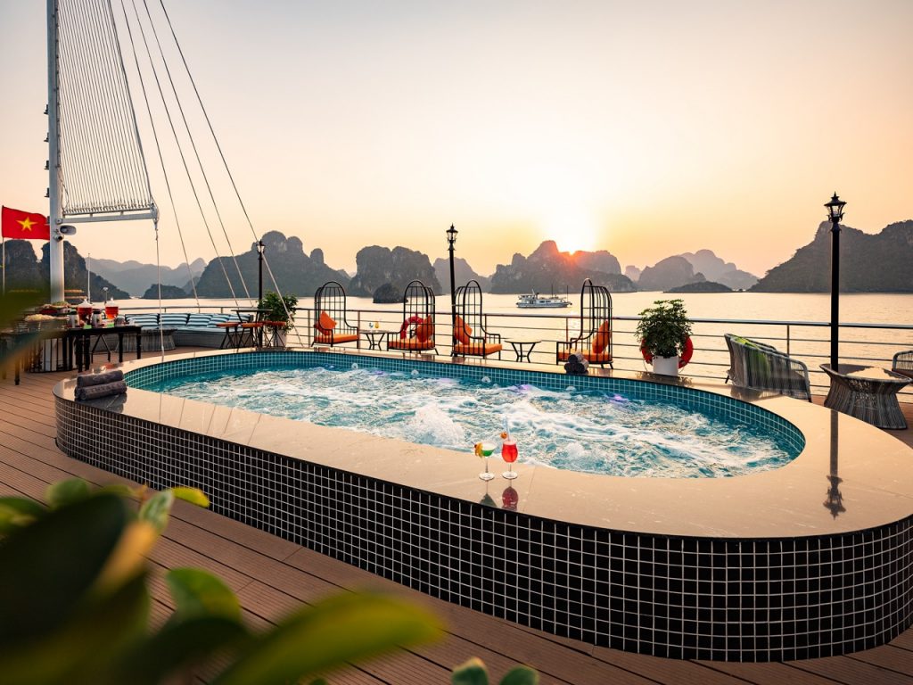Relaxing hot tub on Halong Bay cruise balcony during sunset, scenic limestone karsts in the backgrou.