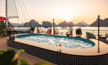 Relaxing hot tub on Halong Bay cruise balcony during sunset, scenic limestone karsts in the backgrou.