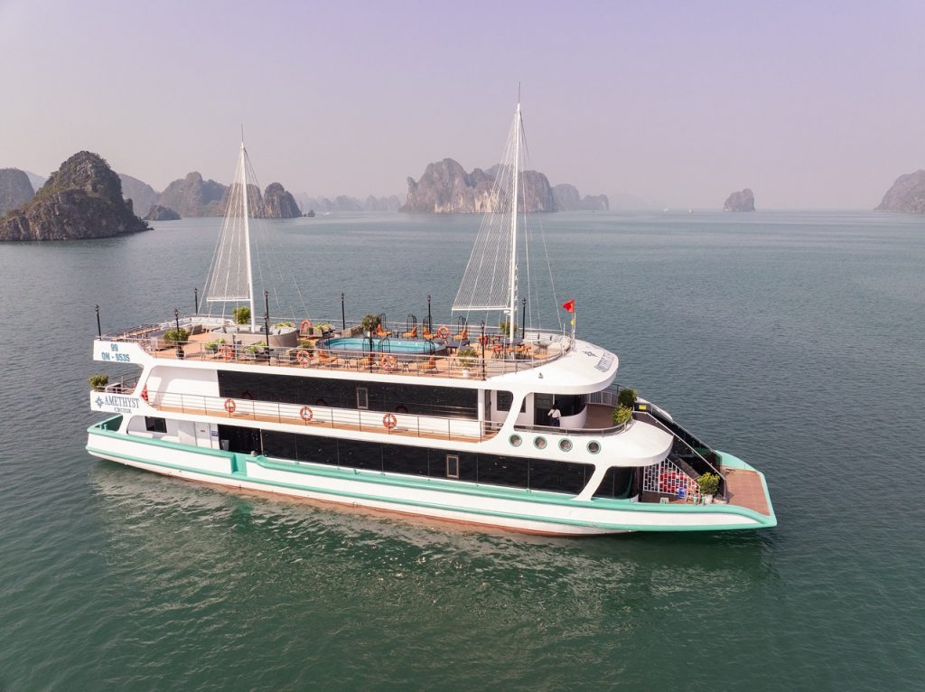 Aerial view of the Amethyst cruise sailing through Halong Bay's emerald waters with limestone karsts.