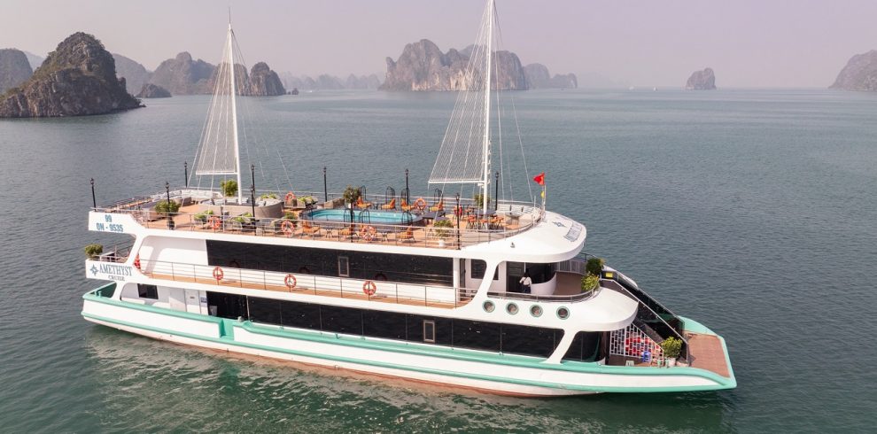 Aerial view of the Amethyst cruise sailing through Halong Bay's emerald waters with limestone karsts.