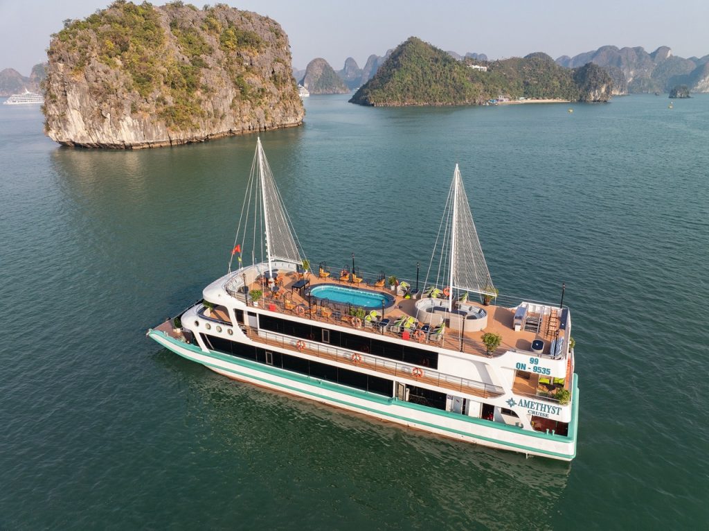 Stunning view of the Amethyst cruise sailing through Halong Bay's emerald waters with limestone kars.