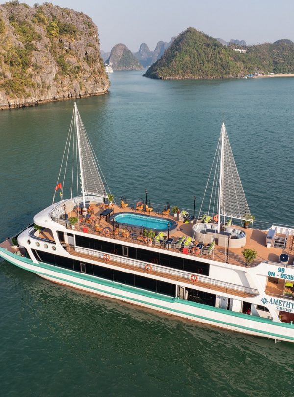 Stunning view of the Amethyst cruise sailing through Halong Bay's emerald waters with limestone kars.