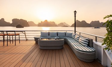 Scenic Halong Bay cruise balcony with sunset view, limestone islands, and tranquil waters.