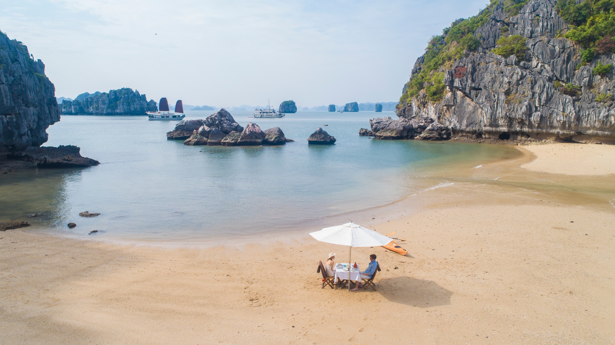 Tranquil Bai Tu Long Bay beach scene with soft sand, calm waters, and lush cliffs, perfect for relax.