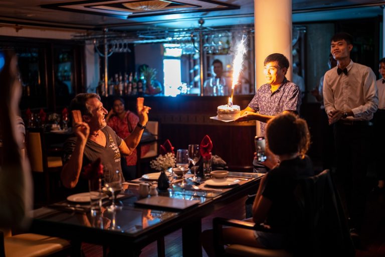 Celebration scene on a luxury Bai Tu Long cruise with guests enjoying a special moment in a cozy, el.