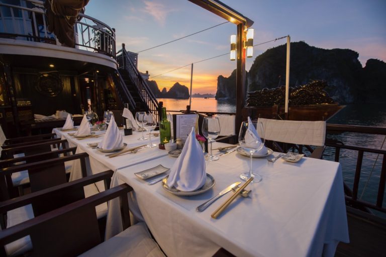 Elegant cruise balcony overlooking Halong Bay with sunset, perfect for romantic dining and scenic re.