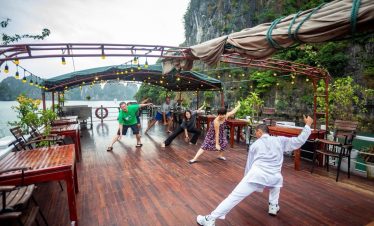 Relaxing Tai Chi session on Bai Tu Long Bay cruise deck at sunrise.