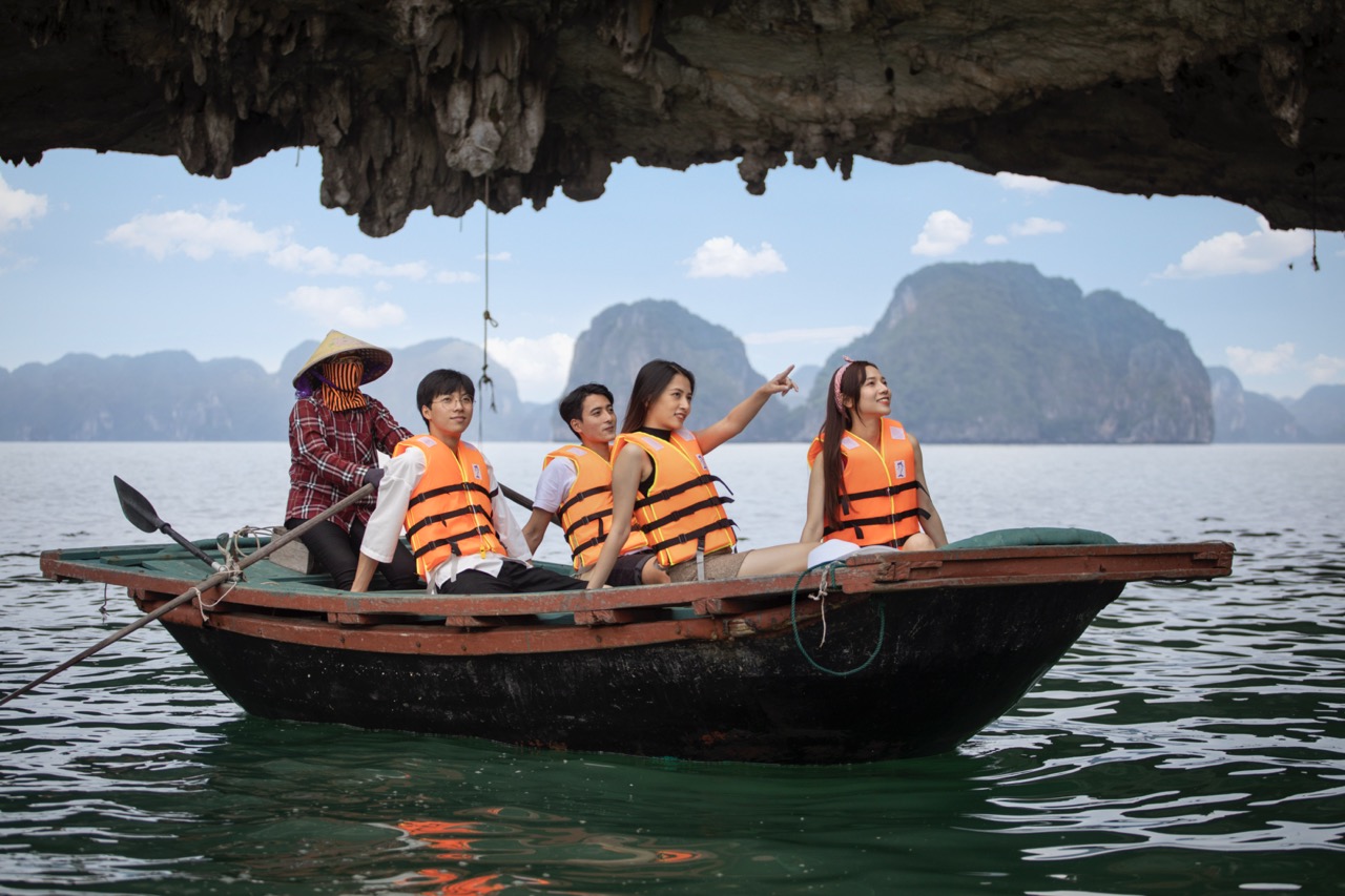 Vivid scene of tourists kayaking under a limestone cave in Halong Bay, showcasing stunning seascape.