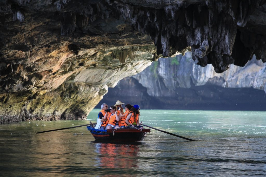 Kayakers exploring Halong Bay's stunning limestone karsts and emerald waters on a peaceful cruise.