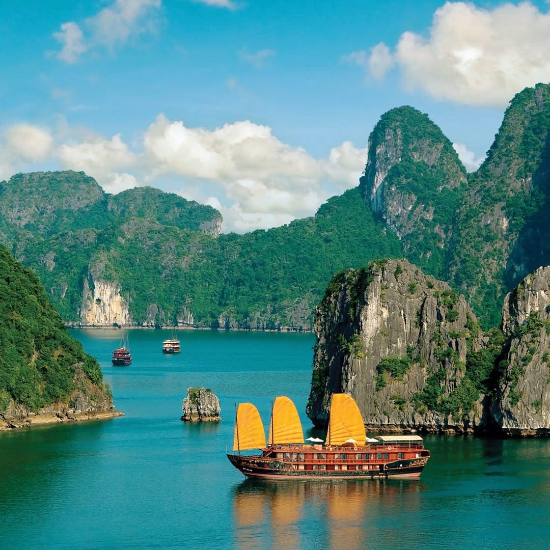 Stunning view of Halong Bay with traditional cruise boat amidst towering limestone karsts and emeral.
