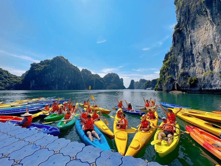 Kayaking in Halong Bay with vibrant boats and stunning limestone karsts.