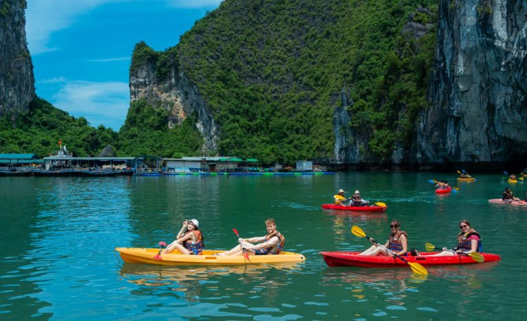 Kayaking in Halong Bay with stunning limestone karsts and emerald waters.
