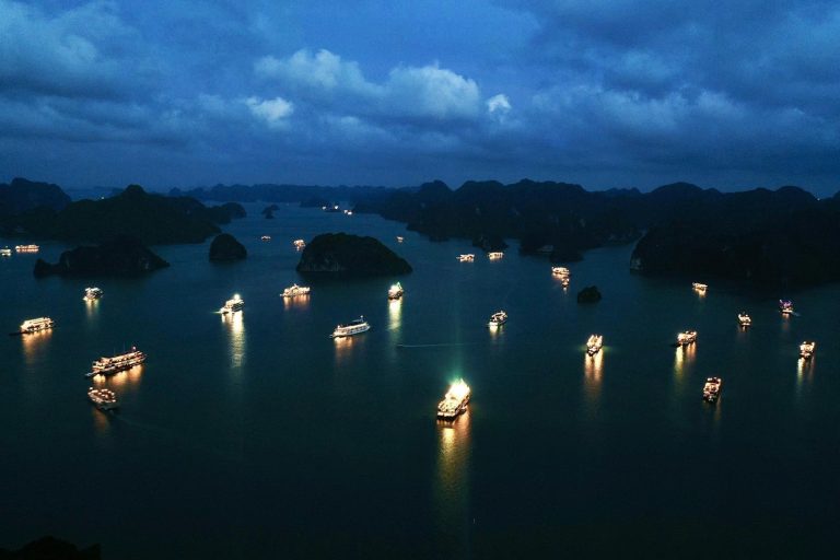 Stunning night view of Halong Bay with illuminated boats and dramatic cloudy sky, perfect for luxury.