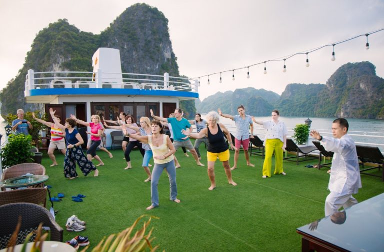 Halong Bay cruise balcony with guests enjoying dance and entertainment on deck.