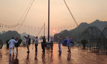 Beautiful sunset over Halong Bay with tourists on a cruise deck, surrounded by limestone karsts and.