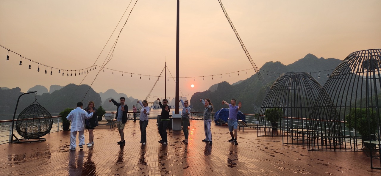 Beautiful sunset over Halong Bay with tourists on a cruise deck, surrounded by limestone karsts and.