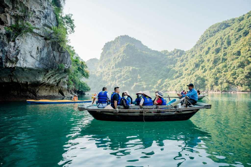 Kayaking tour on Halong Bay featuring travelers exploring the stunning limestone karsts and emerald.