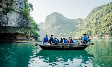 Kayaking tour on Halong Bay featuring travelers exploring the stunning limestone karsts and emerald.