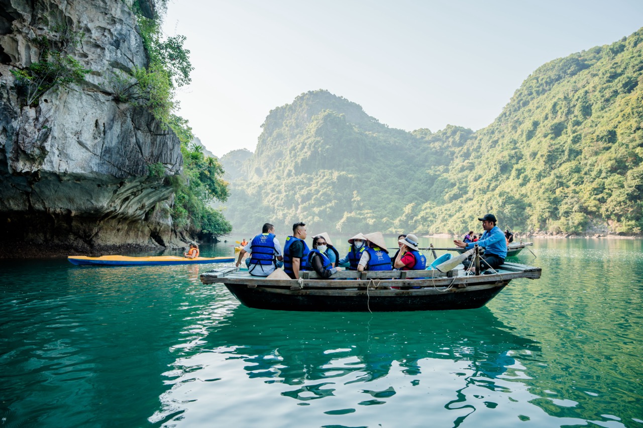 Kayaking tour on Halong Bay featuring travelers exploring the stunning limestone karsts and emerald.